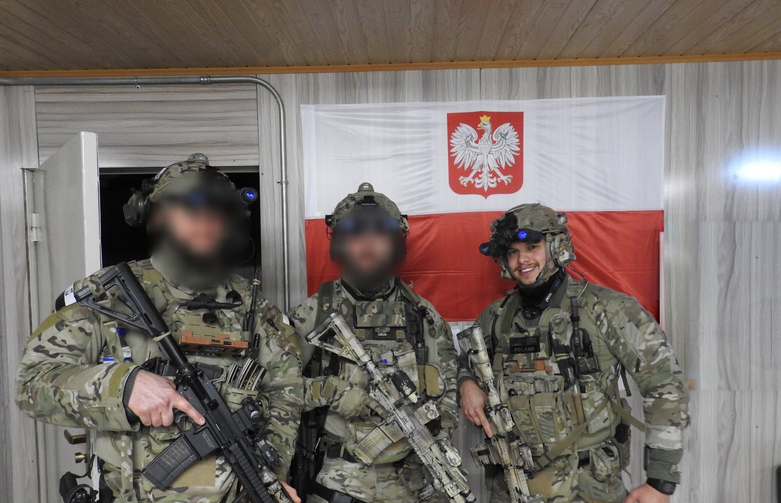 Instruktor w wyposażeniu bojowym, uśmiechnięty, w korytarzu
